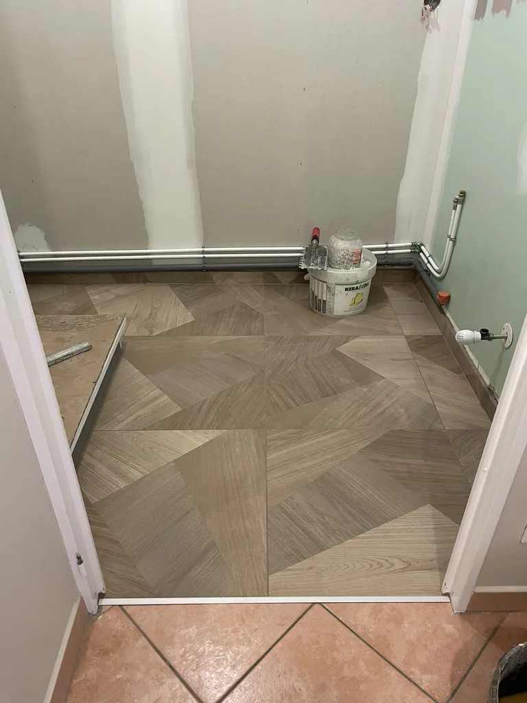 Pose de carrelage au sol dans cette salle de bain rénovée avec douche