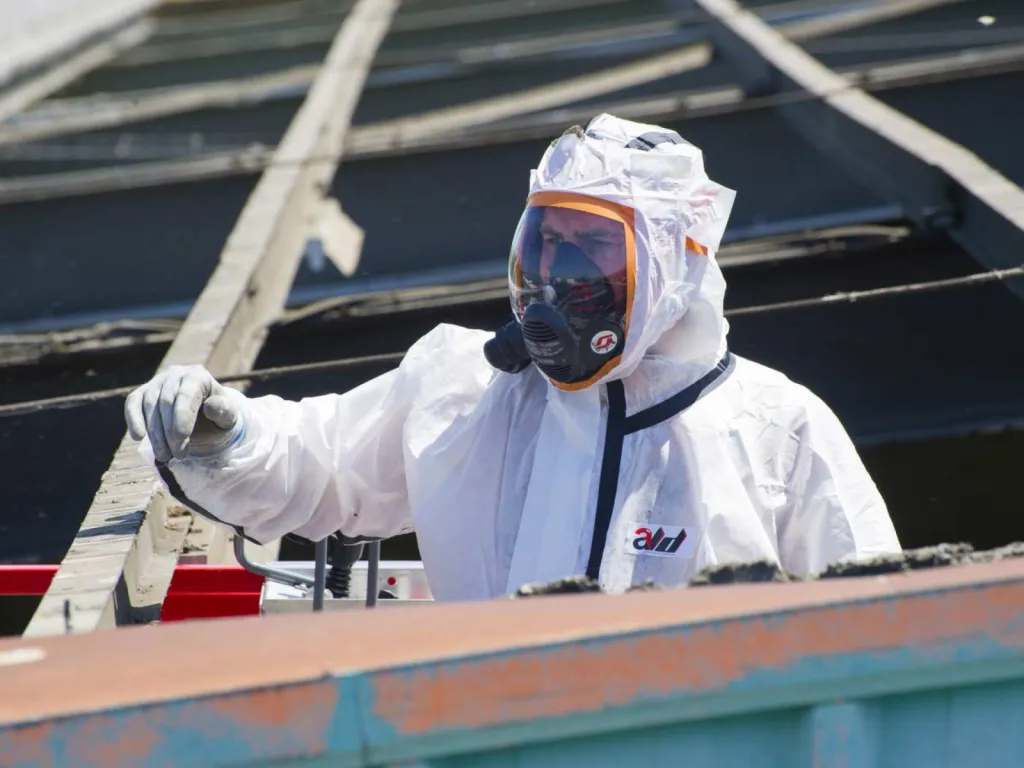 photographe chantier BTP intervention d'un homme équipé sur un toit à désamianté