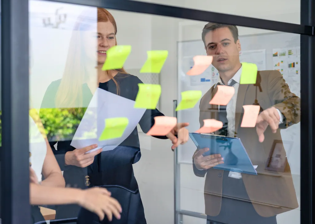 Deux managers organisent des idées sur un tableau lors d’un travail collectif