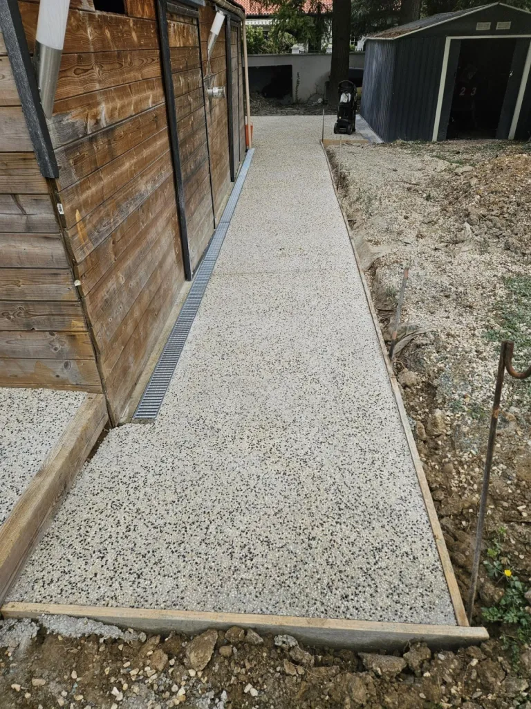 Conception d'une cour complète en béton désactiver avec des chemins d'accès jusqu'à l'escalier extérieur et la cabane de jardin à Meximieux dans l'Ain