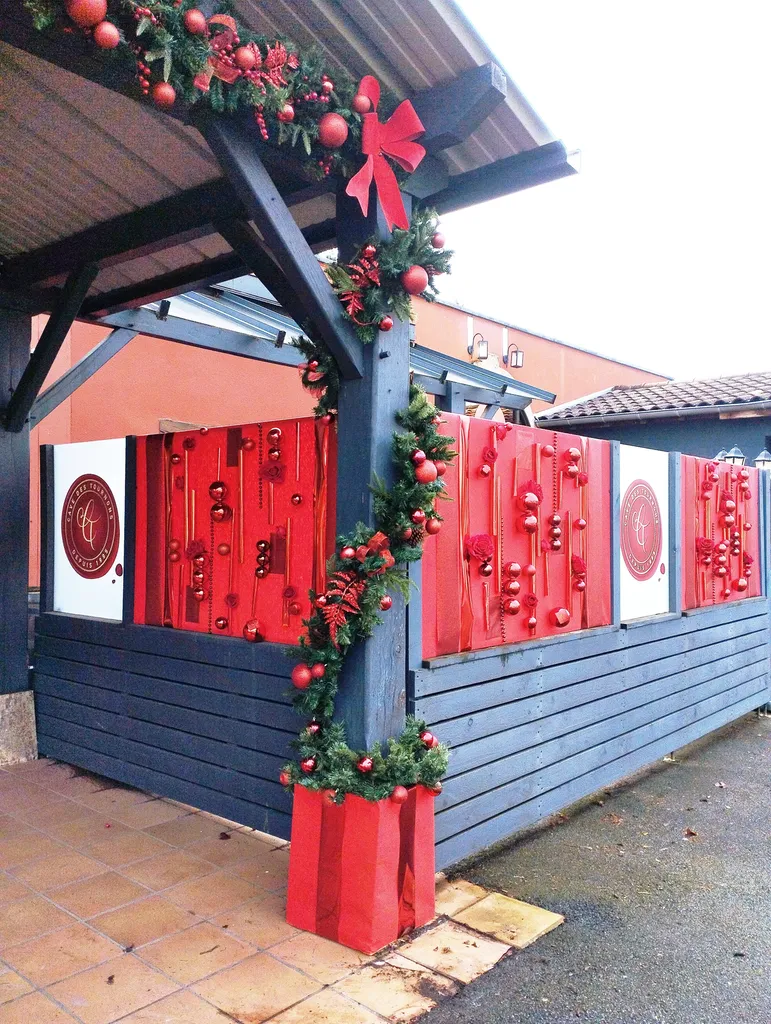 Décoration de Noël de la Cave des Tournons avec sapins synthétiques, guirlandes artificielles et tableaux de Noël garnis de boules rouges gourmandes à Charnay-lès-Mâcon