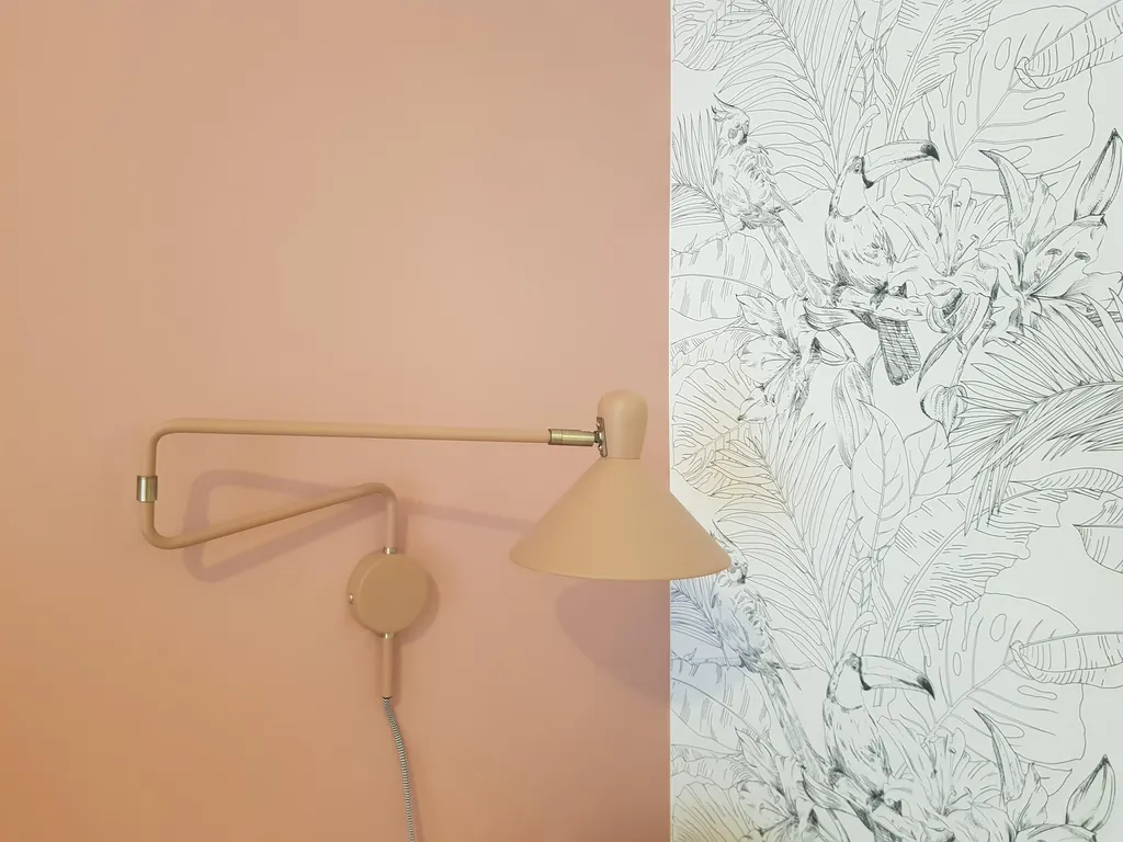 Décoration d’une chambre bureau avec mur rose poudré, papier peint tropical et applique murale articulée dans une maison entre Aix-en-Provence et Ventabren.
