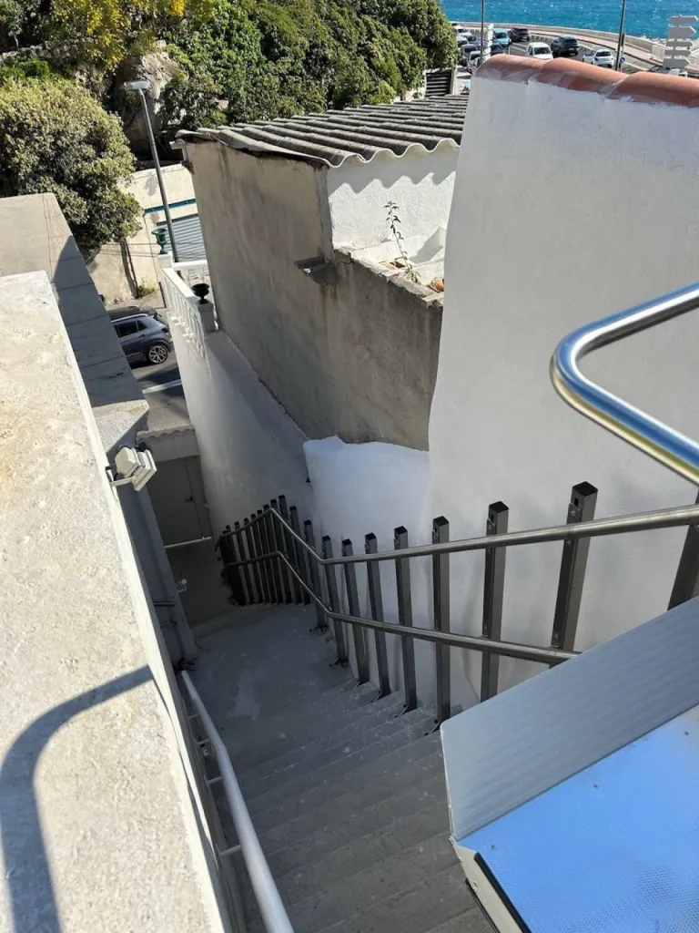 Vue sur les pieds autoporteurs de cette plateforme oblique Lehner Stratos en extérieur dans un escalier droit avec palier intermédiaire à proximité de la mer à Marseille