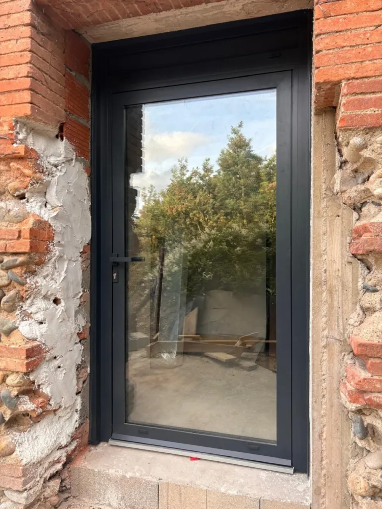 Rénovation avec pose d’une porte vitrée en aluminium dans un bâti ancien à Muret