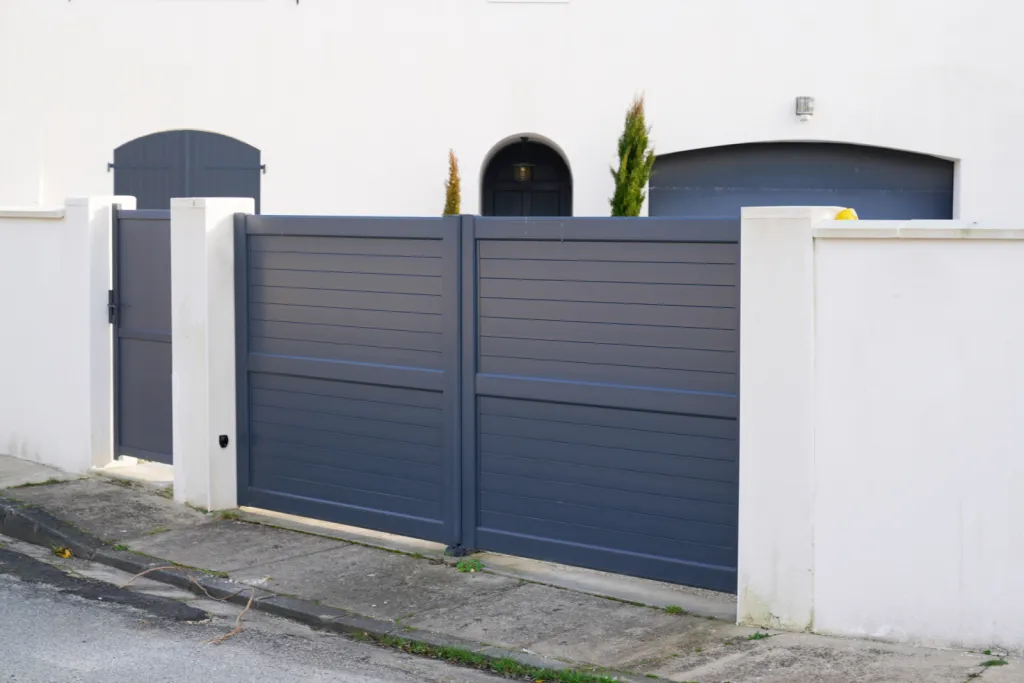 Installation de portail battant électrique plein ou semi-ajouré à Genas, avec tôle décorative et clôture assortie sur muret