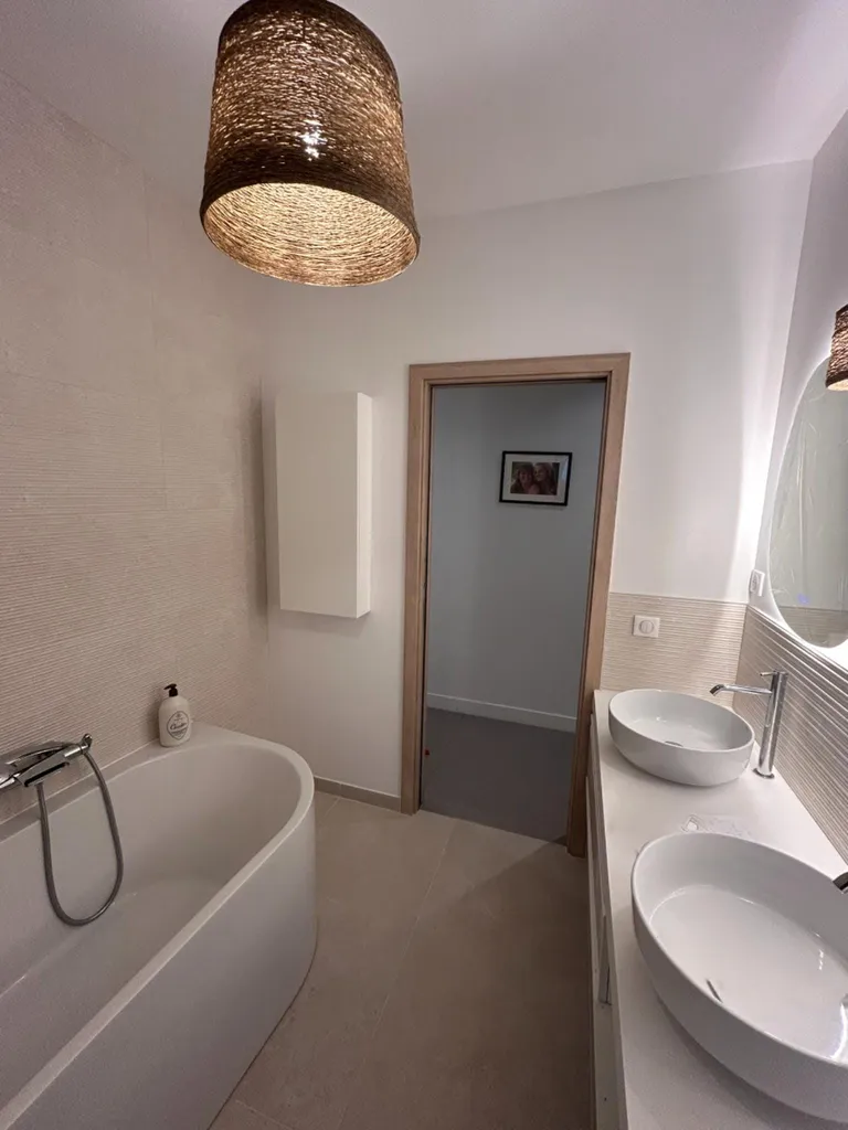 Aménagement d'un espace bain contemporain avec pose d'une baignoire et robinetterie moderne par notre entreprise RGE