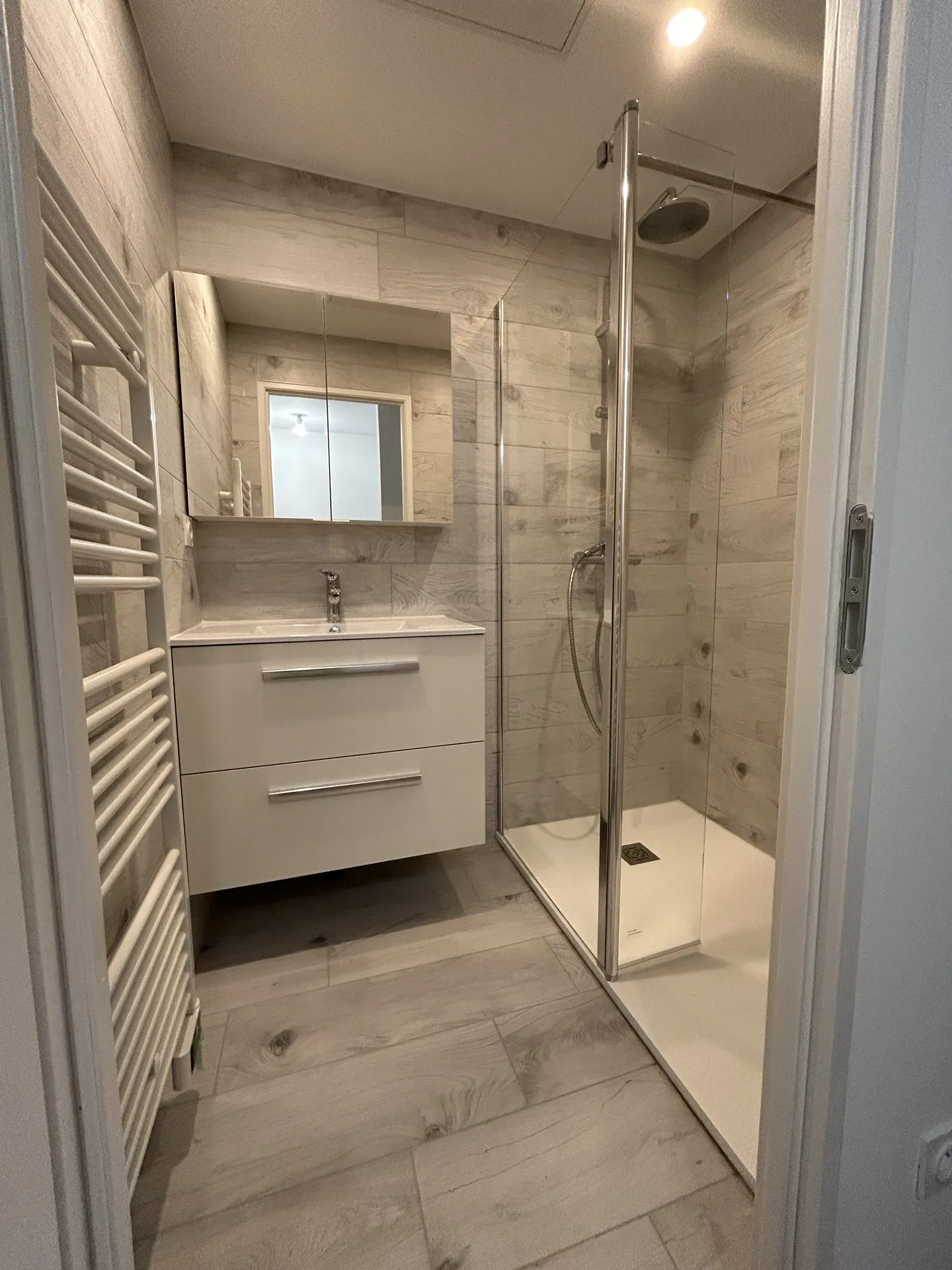 Résultat après travaux par RÉNOVATION by KILLoWATTS : création d’une salle de bain moderne au premier étage avec grand receveur de douche extra-plat Alterna, meuble vasque suspendu et carrelage aspect bois Colorker près de Villefranche-sur-Saône.