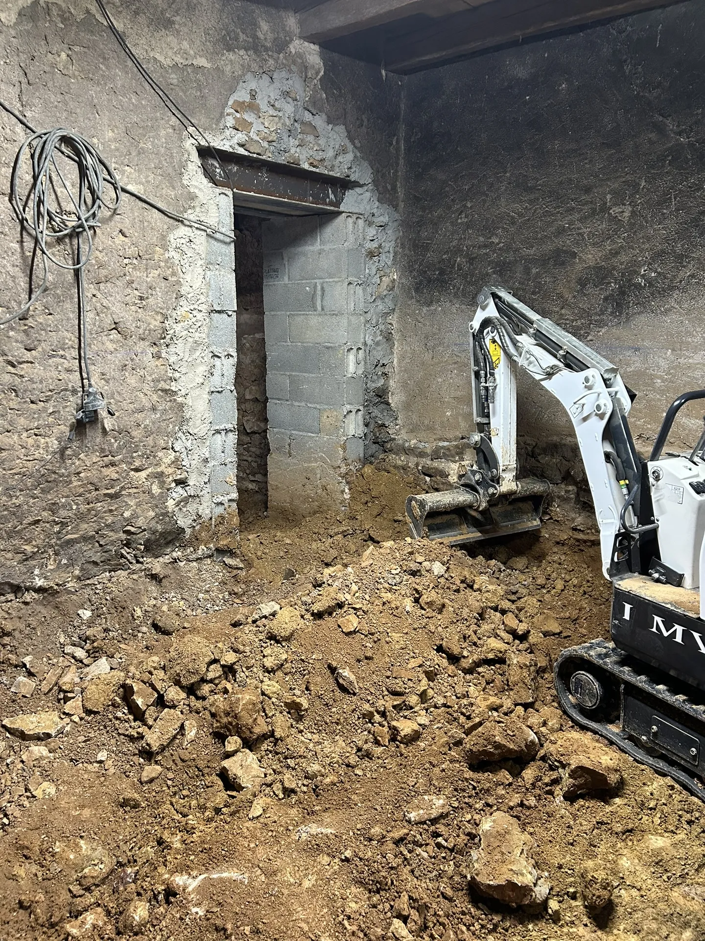 Travaux de décaissement du sol à l’aide d’un mini-engin afin de créer une pièce habitable lors d’une rénovation de maison à Anse (Rhône – 69