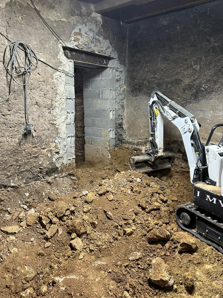 Travaux de décaissement du sol à l’aide d’un mini-engin afin de créer une pièce habitable lors d’une rénovation de maison à Anse (Rhône – 69