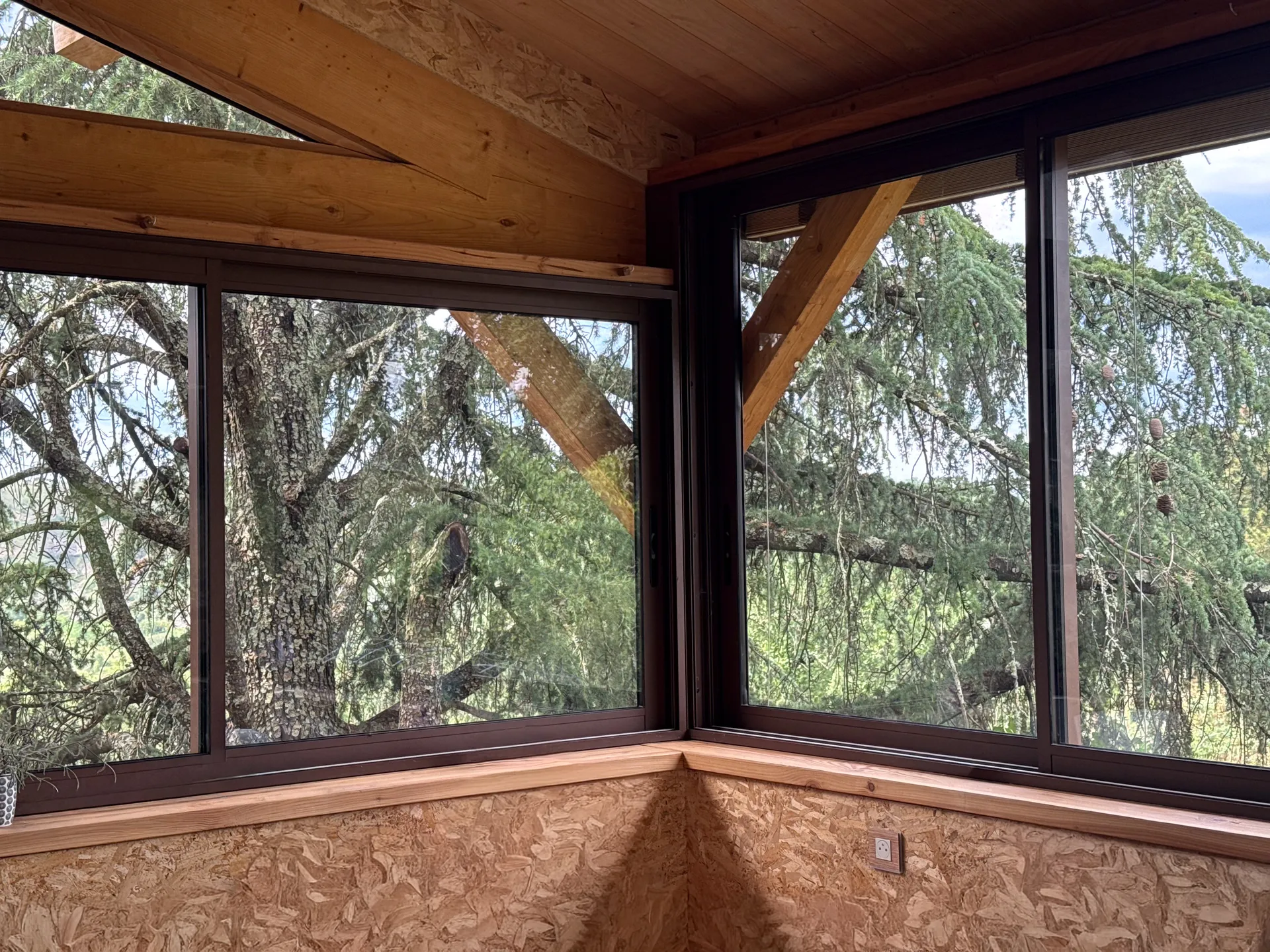 Fermeture d'une terrasse ardéchoise sous charpente bois avec de grands coulissants aluminium teinte rouille
