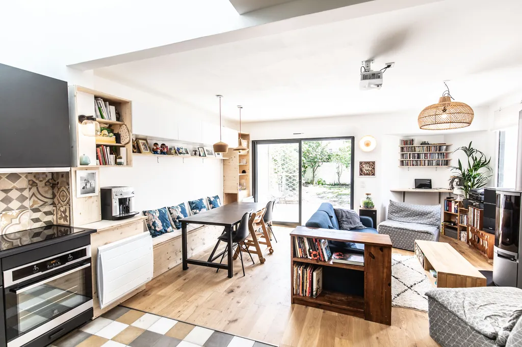 Grande pièce de vie vue depuis la cuisine  AKIKO ARCHITECTURE – Bègles – Rénovation familiale Depuis la cuisine, la pièce de vie se déploie généreusement vers le jardin. Le travail sur les ouvertures apporte une luminosité constante et relie visuellement 