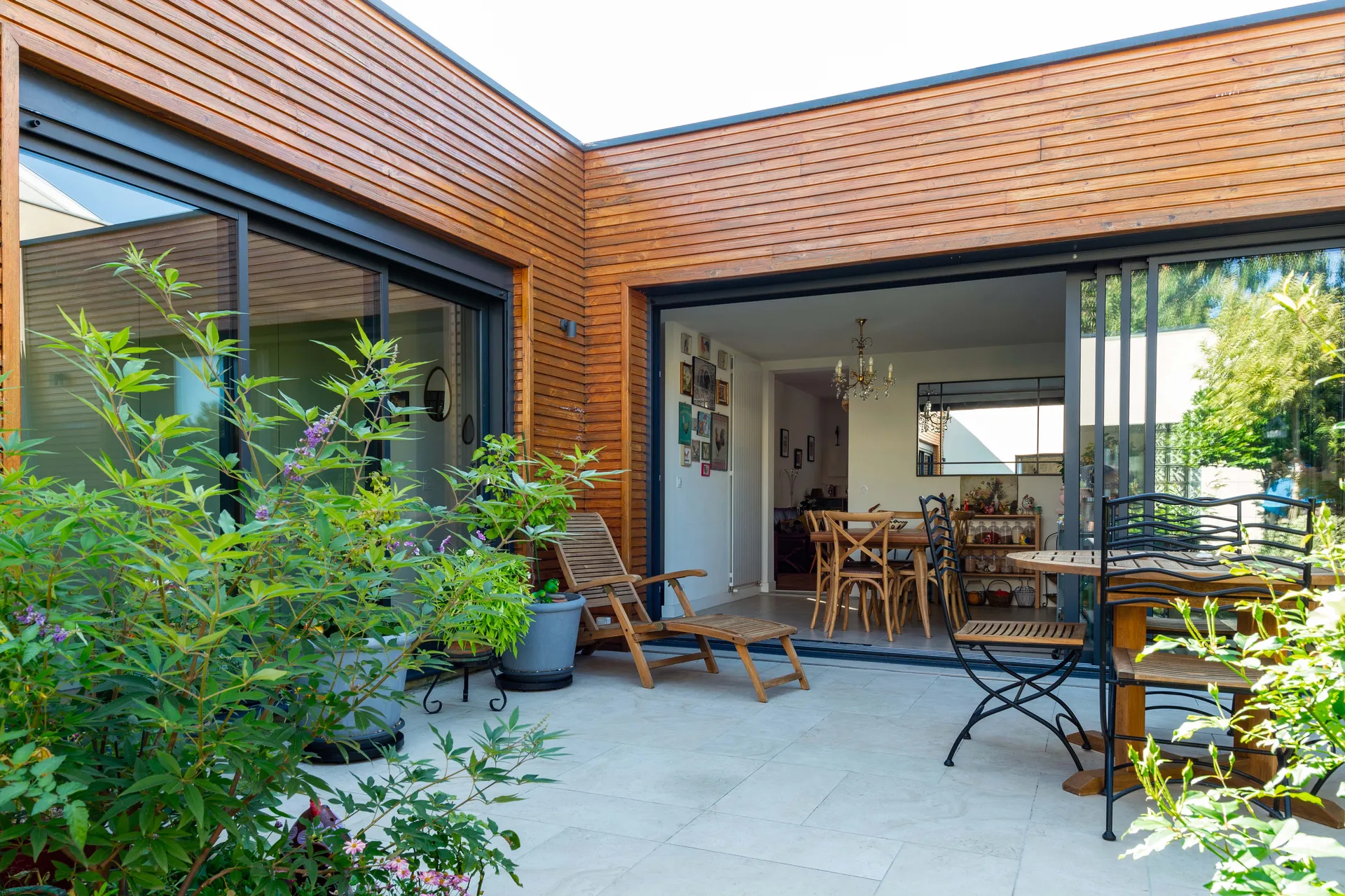 Extension en ossature bois conçue par AKIKO ARCHITECTURE à Bègles : création d’un patio jardin central et de larges baies vitrées reliant la maison et la dépendance pour un dedans-dehors lumineux et apaisant