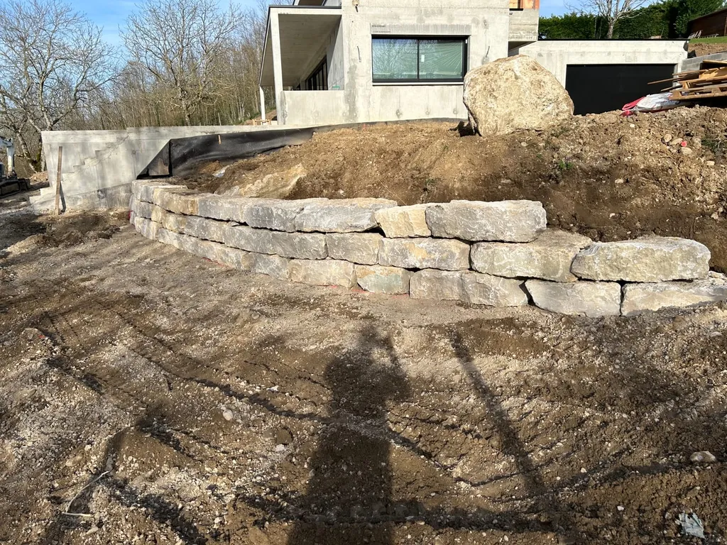 Aménagement extérieur complet à Cailloux-sur-Fontaines : terrassement, mur de soutènement en enrochement et empierrement de cour de maison contemporaine