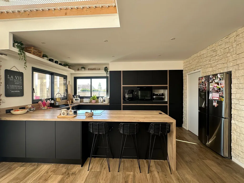 Installation cuisine moderne noire et bois avec grand îlot central dans une construction neuve à Muret (31)