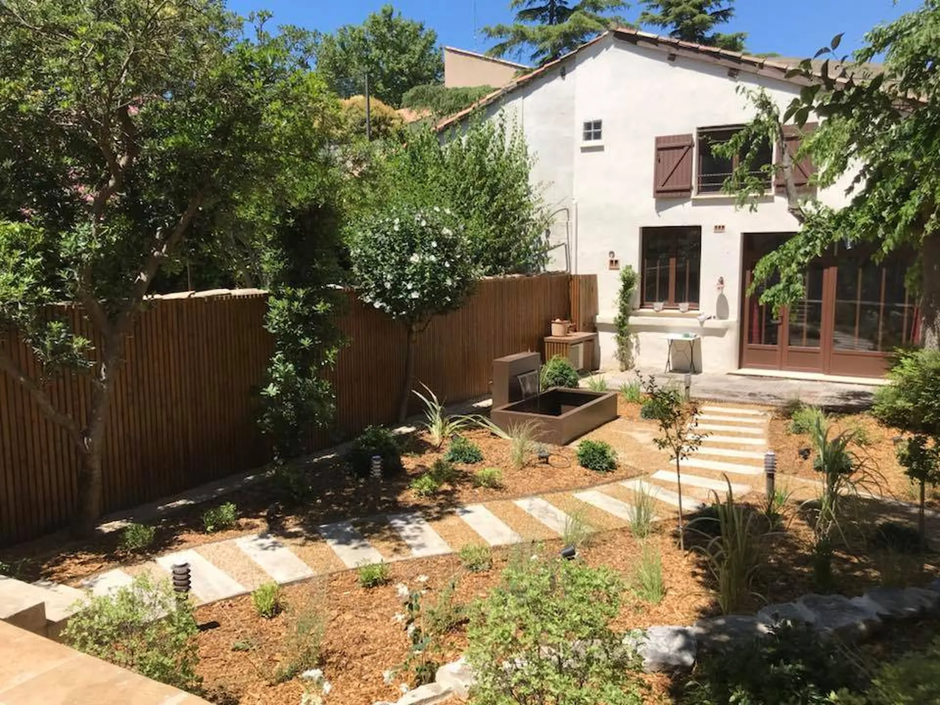 Transformation d’une friche en jardin cosy à Avignon 84000, avec végétaux, fontaine moderne et copeaux de bois