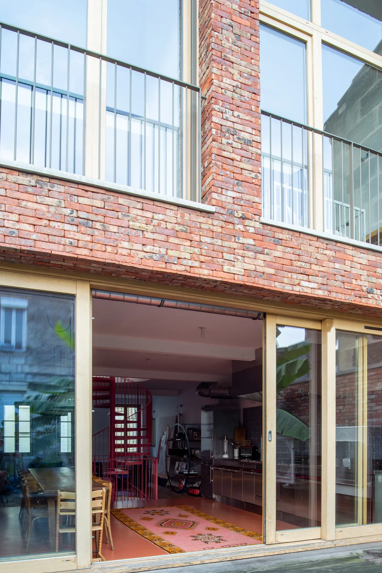 Façade contemporaine en briquette et baies vitrées conçue par AKIKO ARCHITECTURE à Nansouty, offrant une surélévation lumineuse pensée pour les artistes