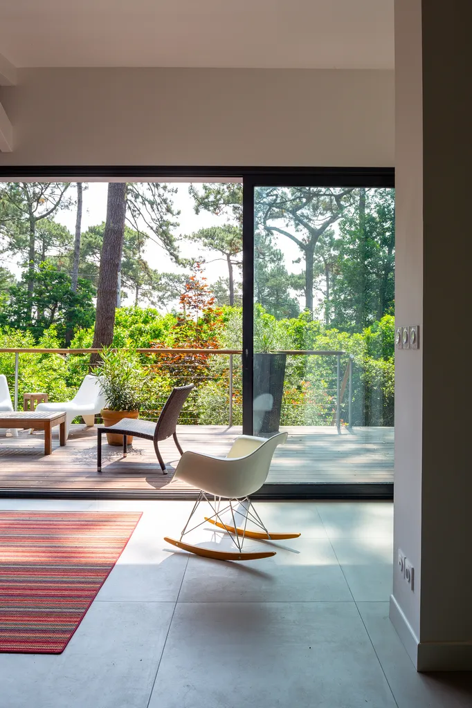 Grande terrasse bois et façade vitrée  AKIKO ARCHITECTURE — Piraillan, Cap-Ferret — rénovation & extension La terrasse bois enveloppe l’extension et crée un véritable belvédère sur la végétation. Le travail du bardage vertical et des débords de toit renfo