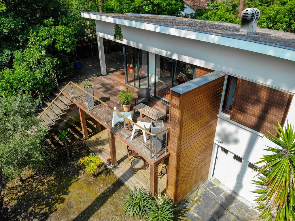 Vue d’ensemble de l’extension et de la terrasse  AKIKO ARCHITECTURE — Piraillan, Cap-Ferret — extension & réhabilitation Depuis la terrasse, on perçoit la finesse du travail structurel : garde-corps en acier, volumes élancés et lien continu entre la maiso