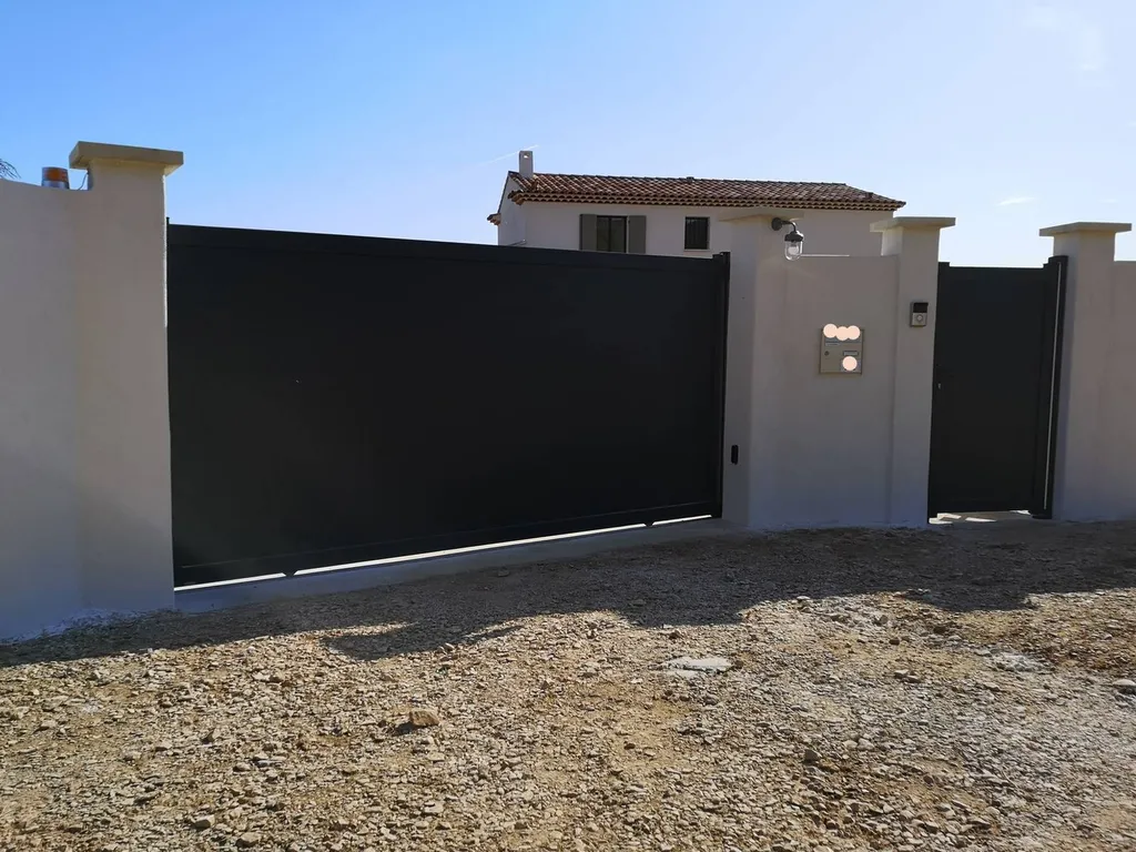 Installation d'un portail en aluminium motorisé de couleur gris anthracite de marque Kostum à Lourmarin dans le 84