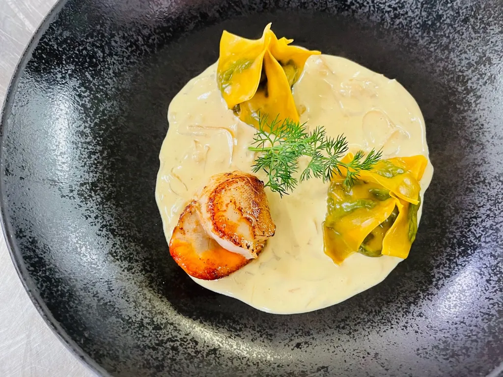 Ravioles de pousses d'épinards, noix de Saint-Jacques snackées dans une crème de moules.