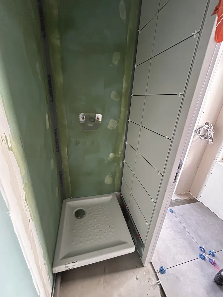 Application rigoureuse d'un Système de Protection à l'Eau sous Carrelage (SPEC) sur plaques hydrofuges avant la pose du receveur de douche extra-plat