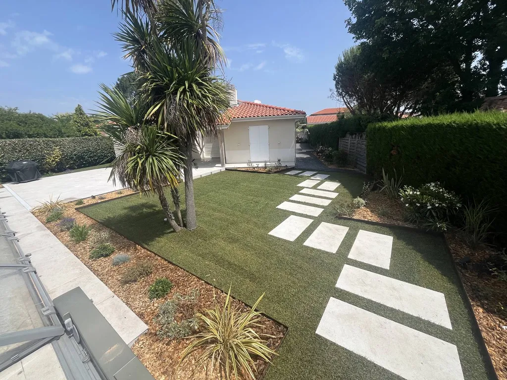 Pelouse d’un jardin transformée en un espace esthétique et fonctionnel près de Bias