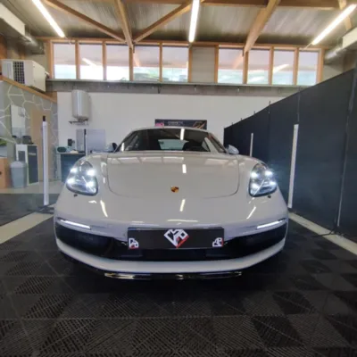 Pose de film de protection PPF FlexiShield sur ailes et bas de caisse d’une Porsche GTS à Clermont-Ferrand avec reproduction stickers Tag Heuer