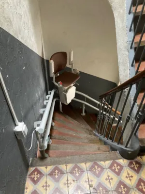 escalier courbe en intérieur équipé d'un fauteuil monte-escalier OTOLIFT