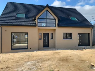 Application d'un enduit projeté jaune sable sur une maison neuve à Goderville (76)
