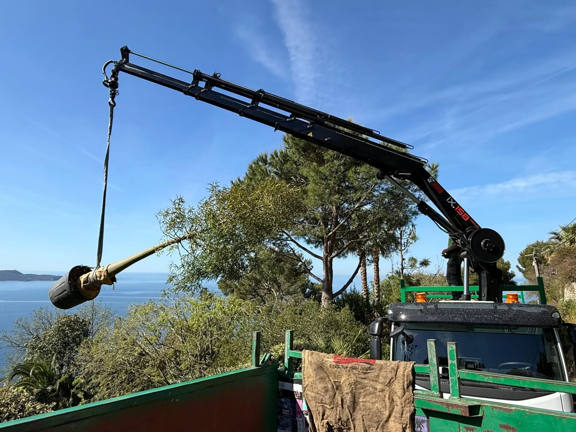 Livraison et mise en place avec la grue des végétaux en motte au Mont des Oiseaux à Carqueiranne, avec vue sur la mer Méditerranée. 