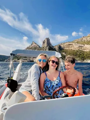 Famille à bord d'un bateau semi-rigide de L'Eden Boat dans les Calanques, parents et enfants souriants sous le soleil de Provence
