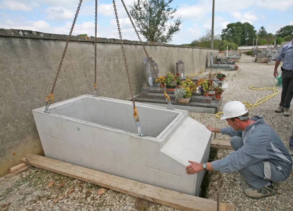 Caveau préfabriqué monobloc en cours de pose par grutage dans une tombe à Rillieux la Pape