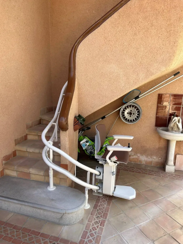 Fauteuil monte-escalier OTOLIFT TWO en extérieur sur sa base de départ au bas de l'escalier à St Cyr sur Mer près de Marseille Fauteuil monte-escalier OTOLIFT TWO en extérieur sur sa base de départ au bas de l'escalier à St Cyr sur Mer près de Marseille