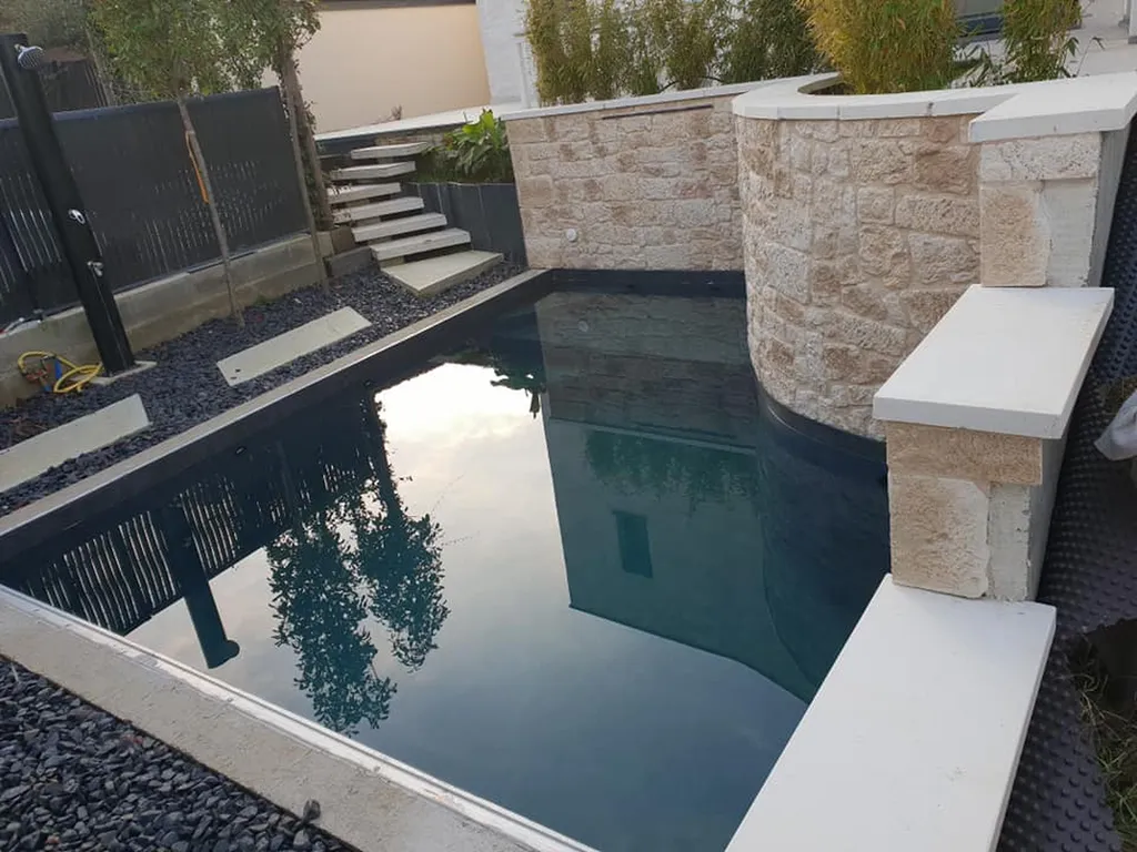 Construire une piscine coque design avec muret de soutènement en pierre naturelle et aménagement paysager sur mesure à Muret et Tournefeuille