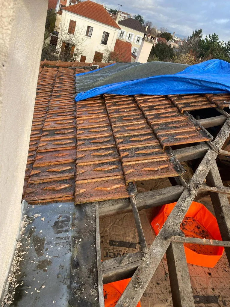 Artisan couvreur réalisant l'isolation thermique d'une toiture traditionnelle en tuiles dans le Val-de-Marne pour une étanchéité durable
