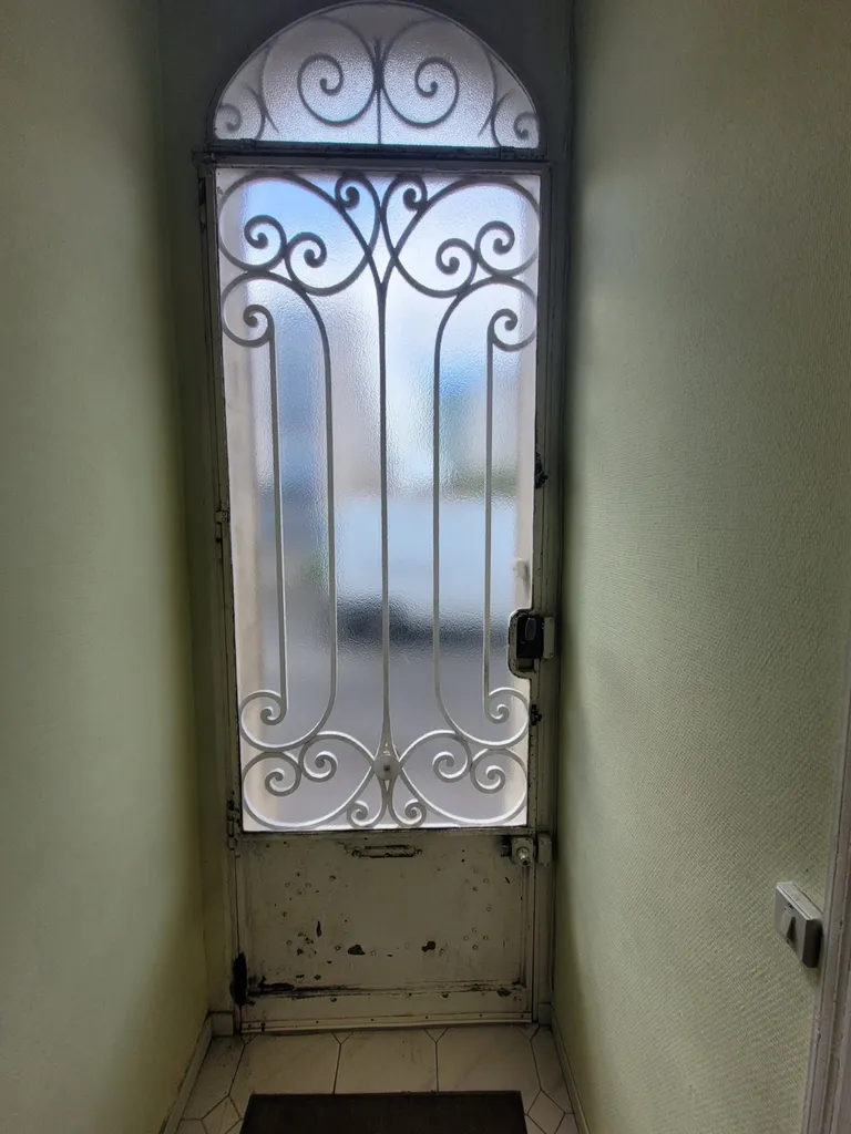 Une porte vitrée et en fer forgée à Bégles