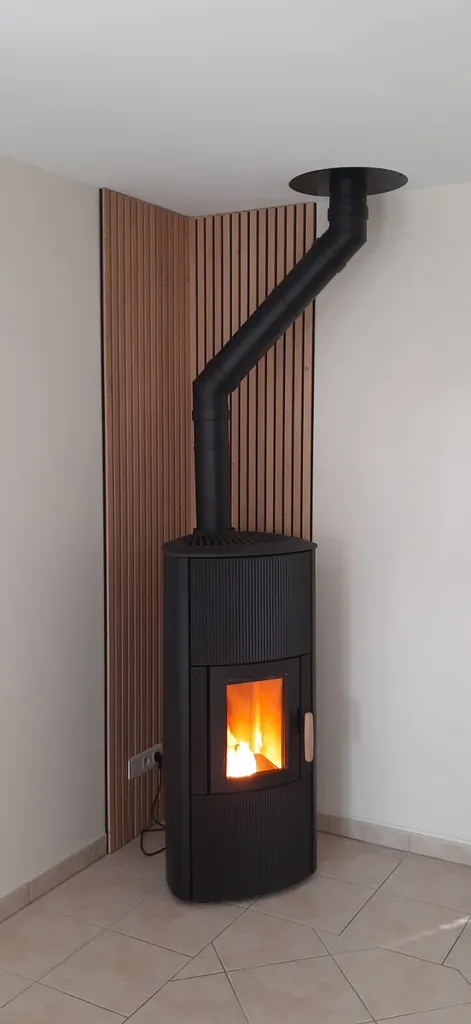 Poêle à granulés Jotul PF 861 S noir contre un mur avec des parements en lame de bois et un sol en carrelage