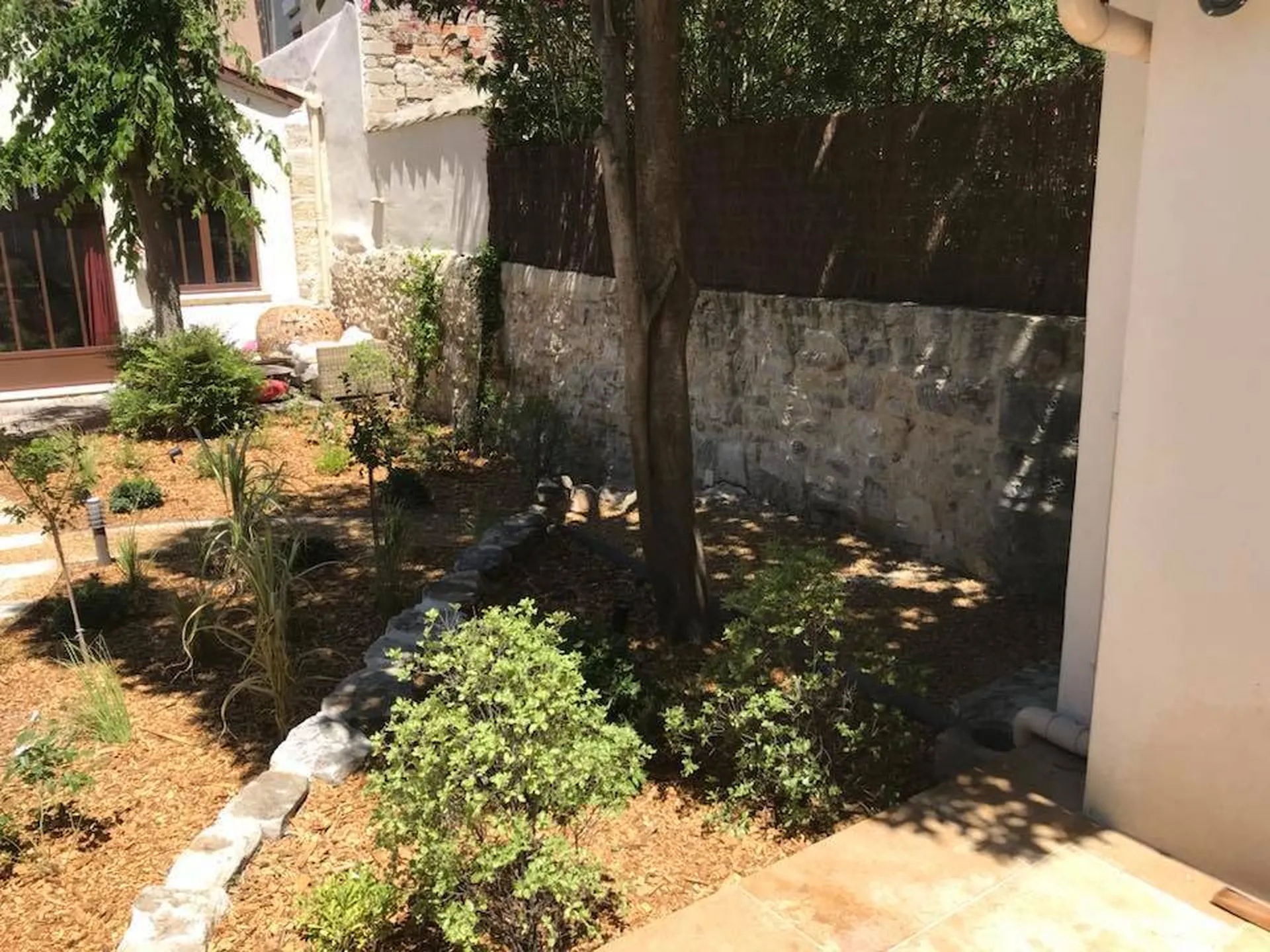 Aménagement paysager unique à Avignon 84000, avec des végétaux, une fontaine moderne et des copeaux de bois pour un jardin tendance