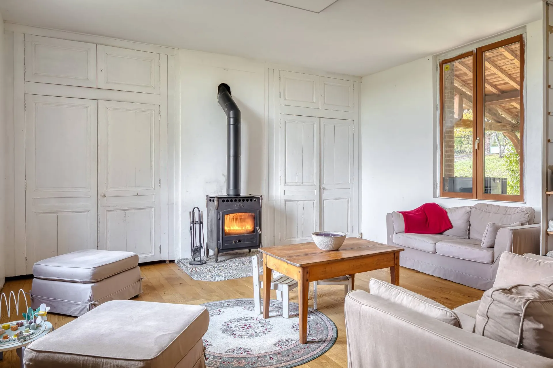 Vends chaleureuse pièce de vie avec poêle à bois ouverte sur une cuisine équipée.