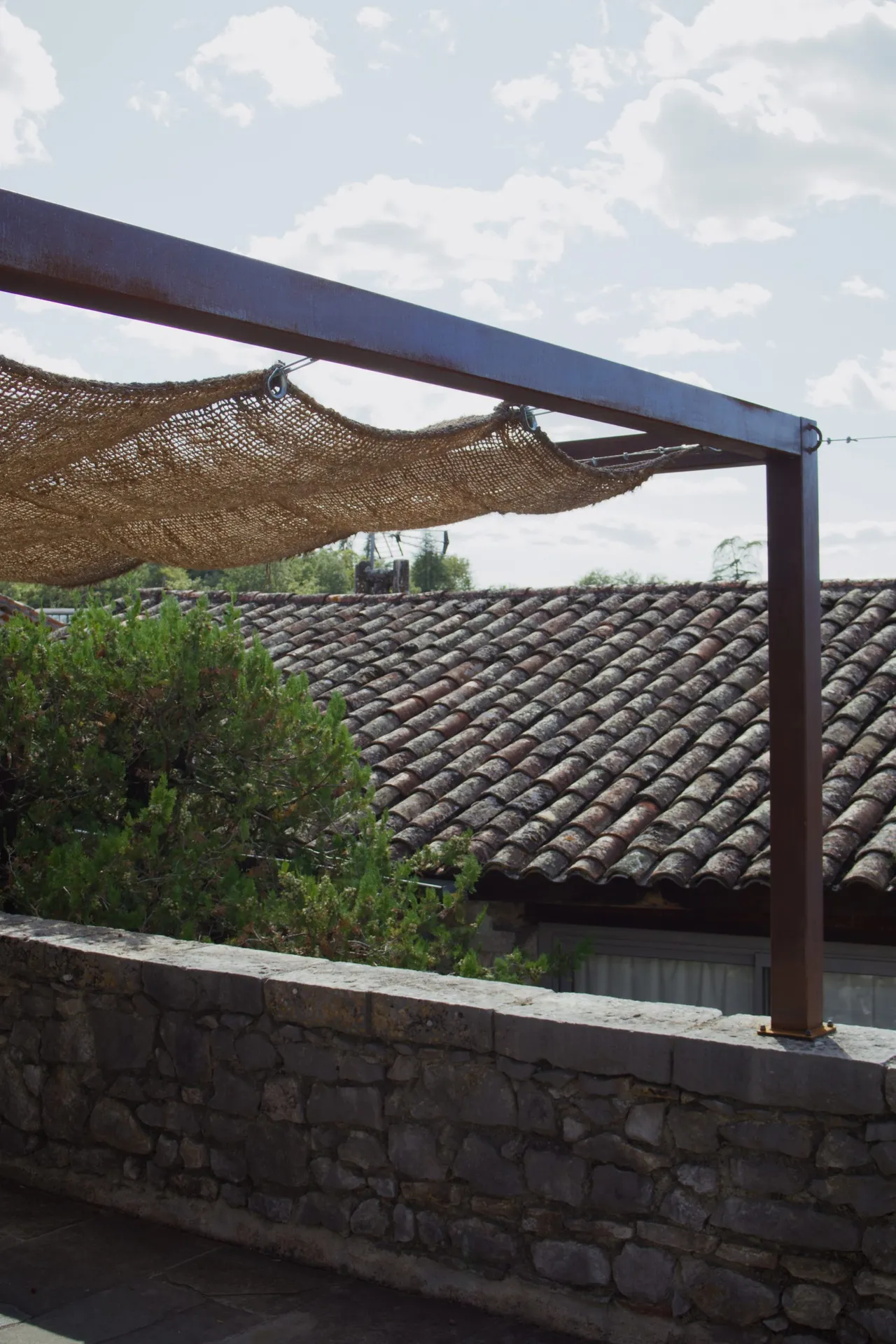 Pergola en fer effet rouille avec une toile de jute au château de balazuc pour une harmonie parfaite.
