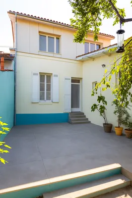 Façade contemporaine imaginée par AKIKO ARCHITECTURE dans le quartier Bastide à Bordeaux, issue d’une surélévation en ossature bois et bardage fibro-ciment ouvrant généreusement la maison sur le jardin