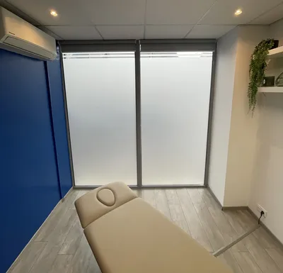 Mise en place d'un film dépoli occultant pour une salle de soins dans un cabinet d'ostéopathie à Besançon. Une solution idéale pour allier lumière naturelle et respect de l'intimité des patients.
