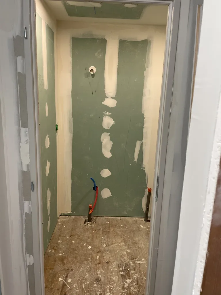 Étape technique de plâtrerie avec la réalisation minutieuse des bandes à joint et le ratissage des supports avant l'application des peintures de finition.