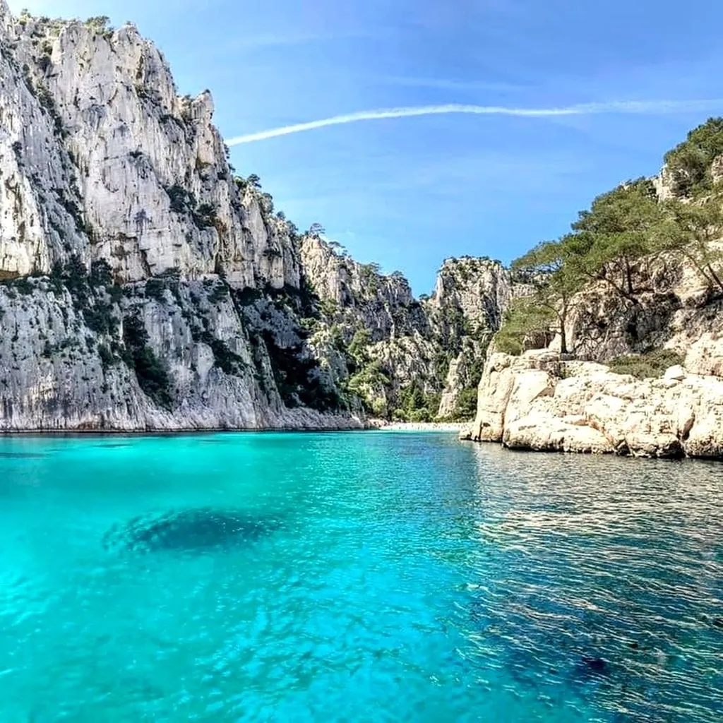 View from an L'Eden Boat semi-rigid over the Calanques cliffs in spring, green vegetation and turquoise sea under a clear sky
