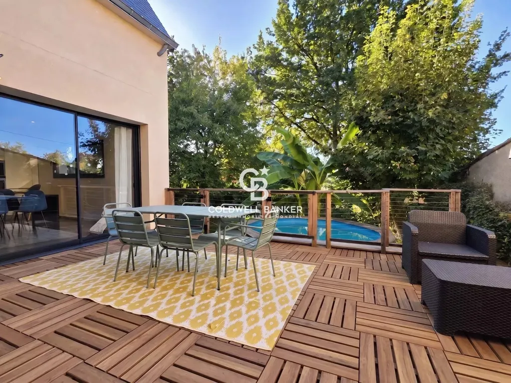 Terrasse en bois surplombant la piscine hors-sol et le jardin arboré