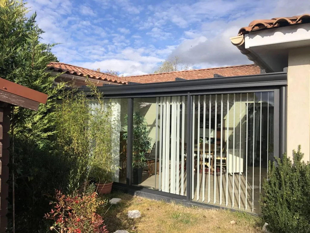 Installation de stores à bandes verticales sur la façade d'une véranda en aluminium TECHNAL à Puyricard