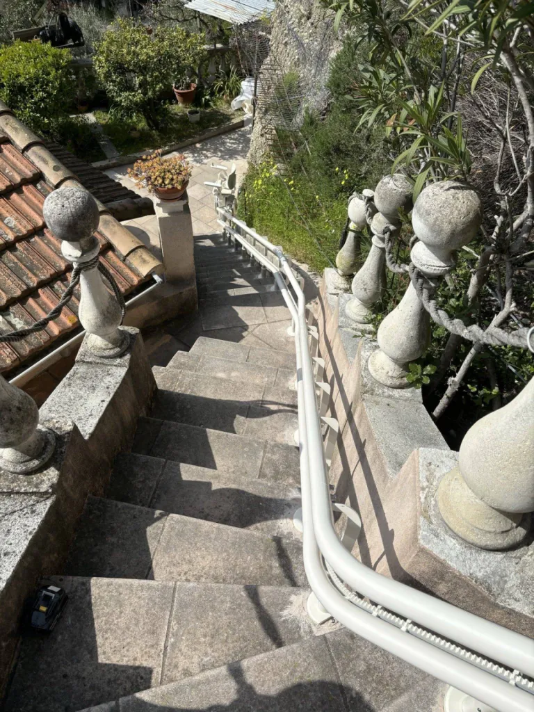 Les rails au plus près du mur pour ce fauteuil monte-escalier OTOLIFT TWO en extérieur dans escalier courbe de 30 m de long à Fréjus