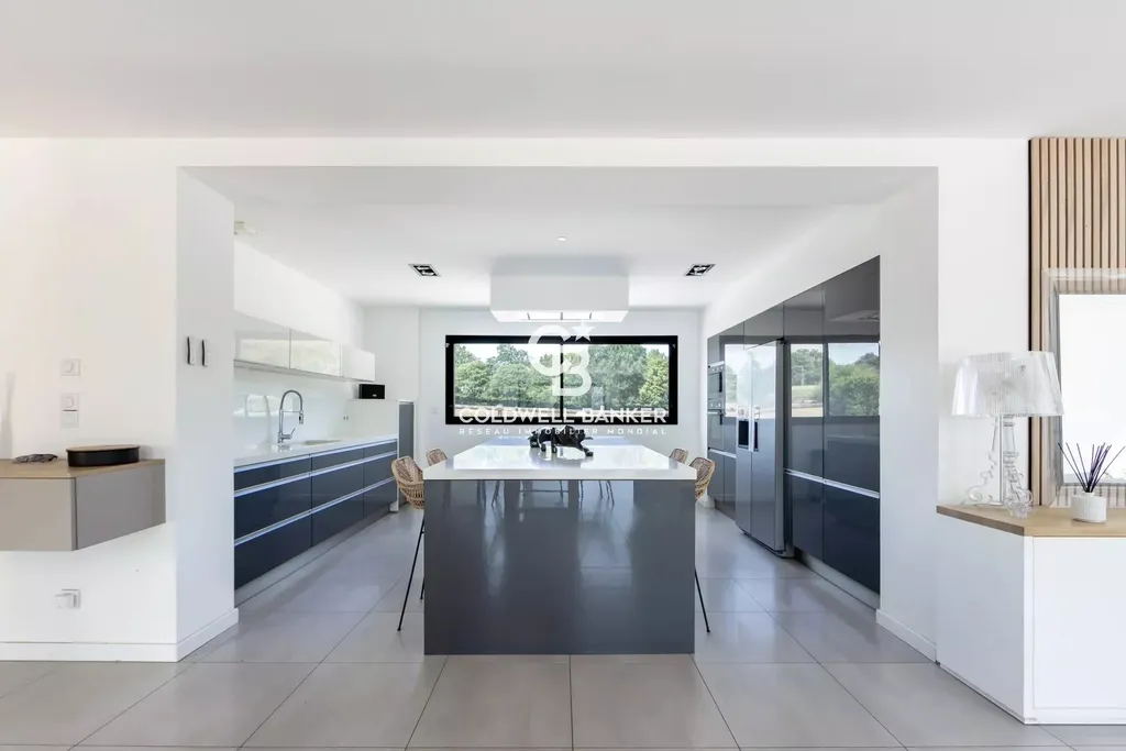 Cuisine ouverte avec îlot central et vue sur le jardin, maison contemporaine à vendre proche Le Mans