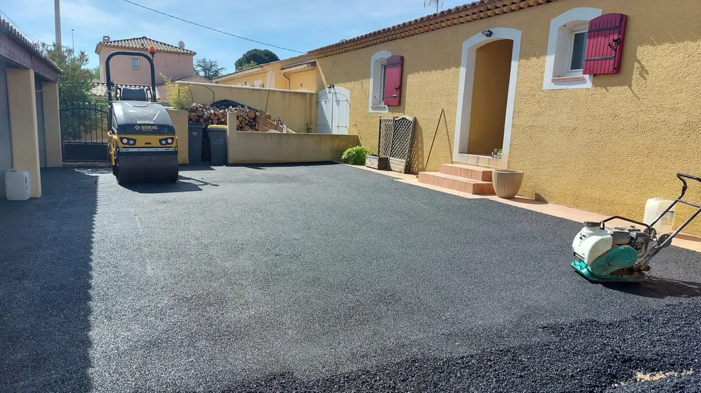 Application d'enrobé de bitume noir dans la cour d'une villa à Saint-Maximin la Sainte-Baume, dans le Var