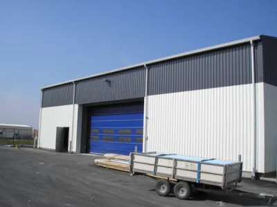 Hangar équipé de gouttières en corniche et de descentes cylindriques.